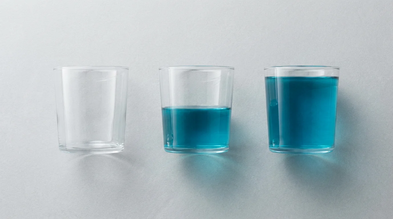 A flat lay of three glasses showing empty, half-full, and full levels of blue liquid.